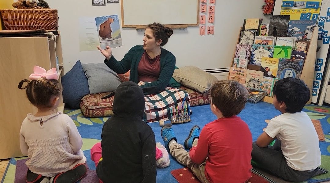 Person reading a book to children in a classroom