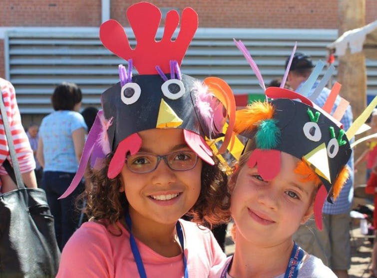 Two children wearing handmade chicken hats