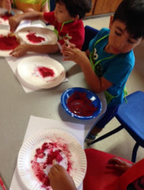 Children doing an art project with red paint on paper plates