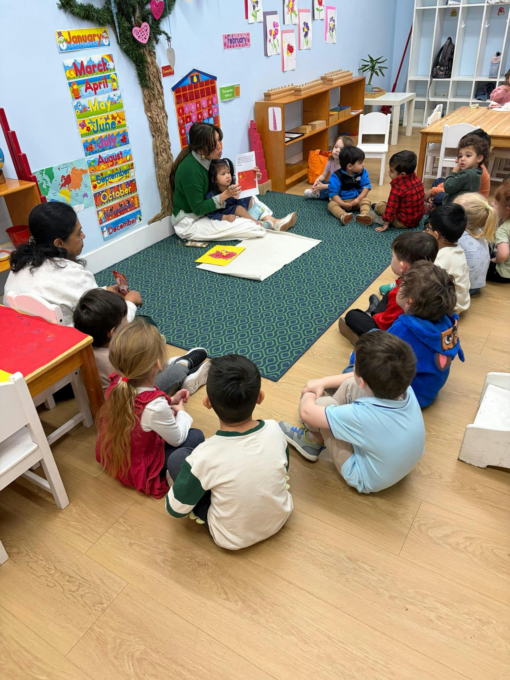 Adult reading a book to a child in their lap and other children seated around
