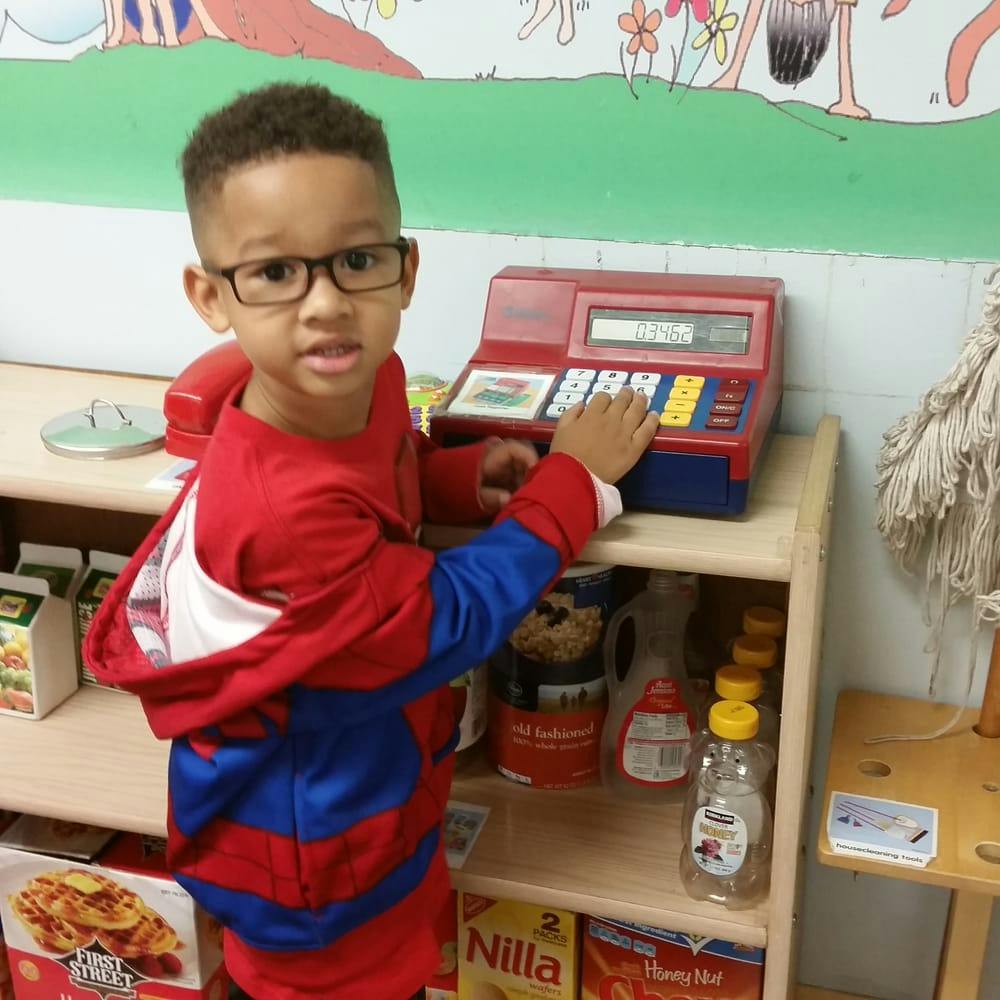 Child in glasses playing with a toy cash register
