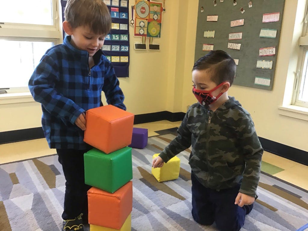 Two children playing with colorful blocks in a classroom