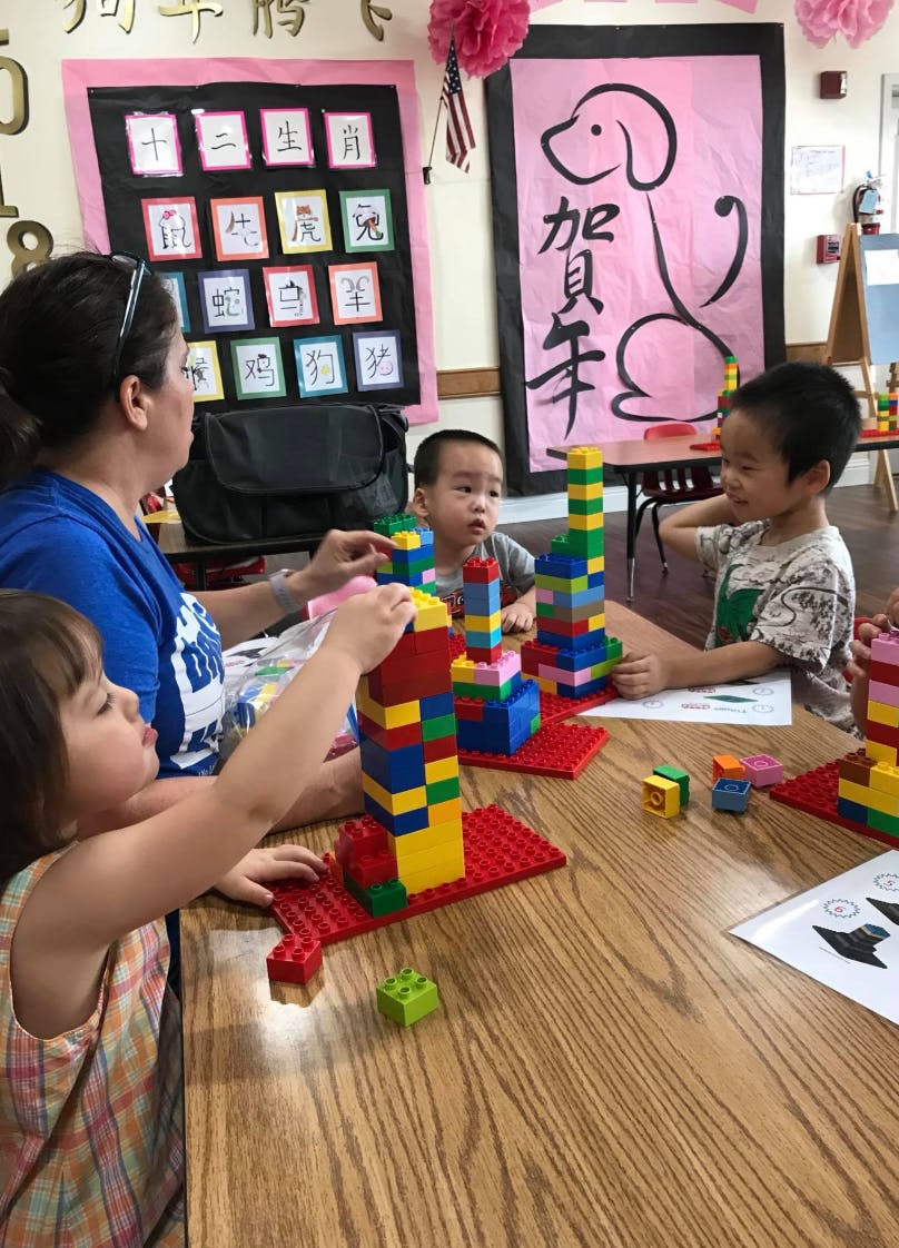 Adult and three children building with colorful blocks at a table