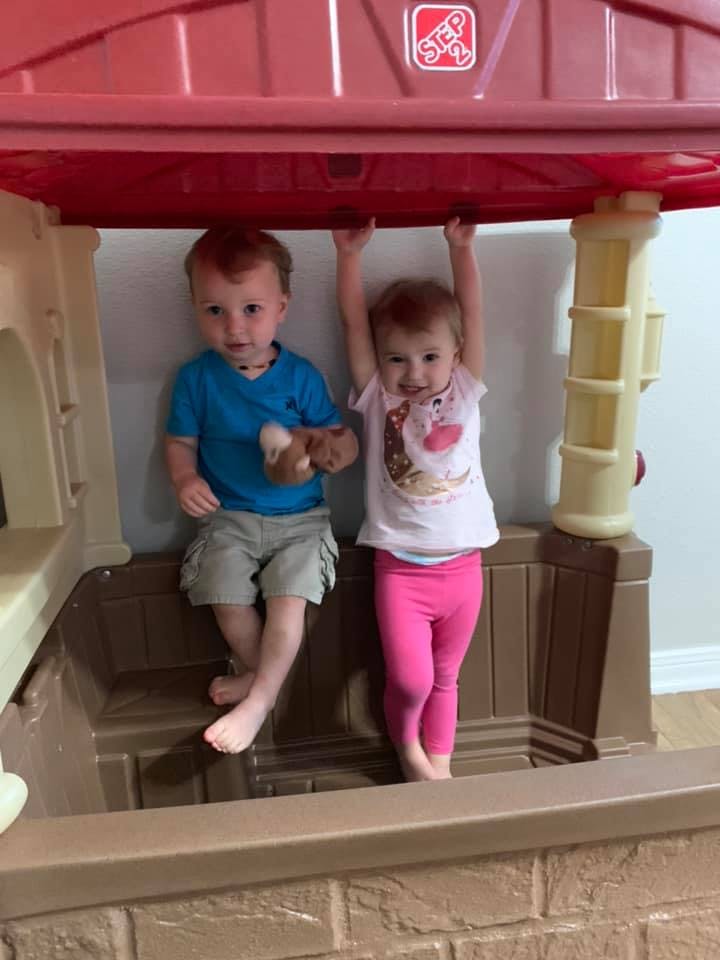 Two children playing in a plastic playhouse