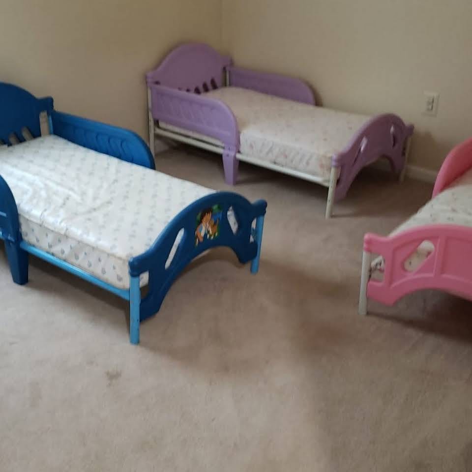 Three toddler beds with mattresses in a room