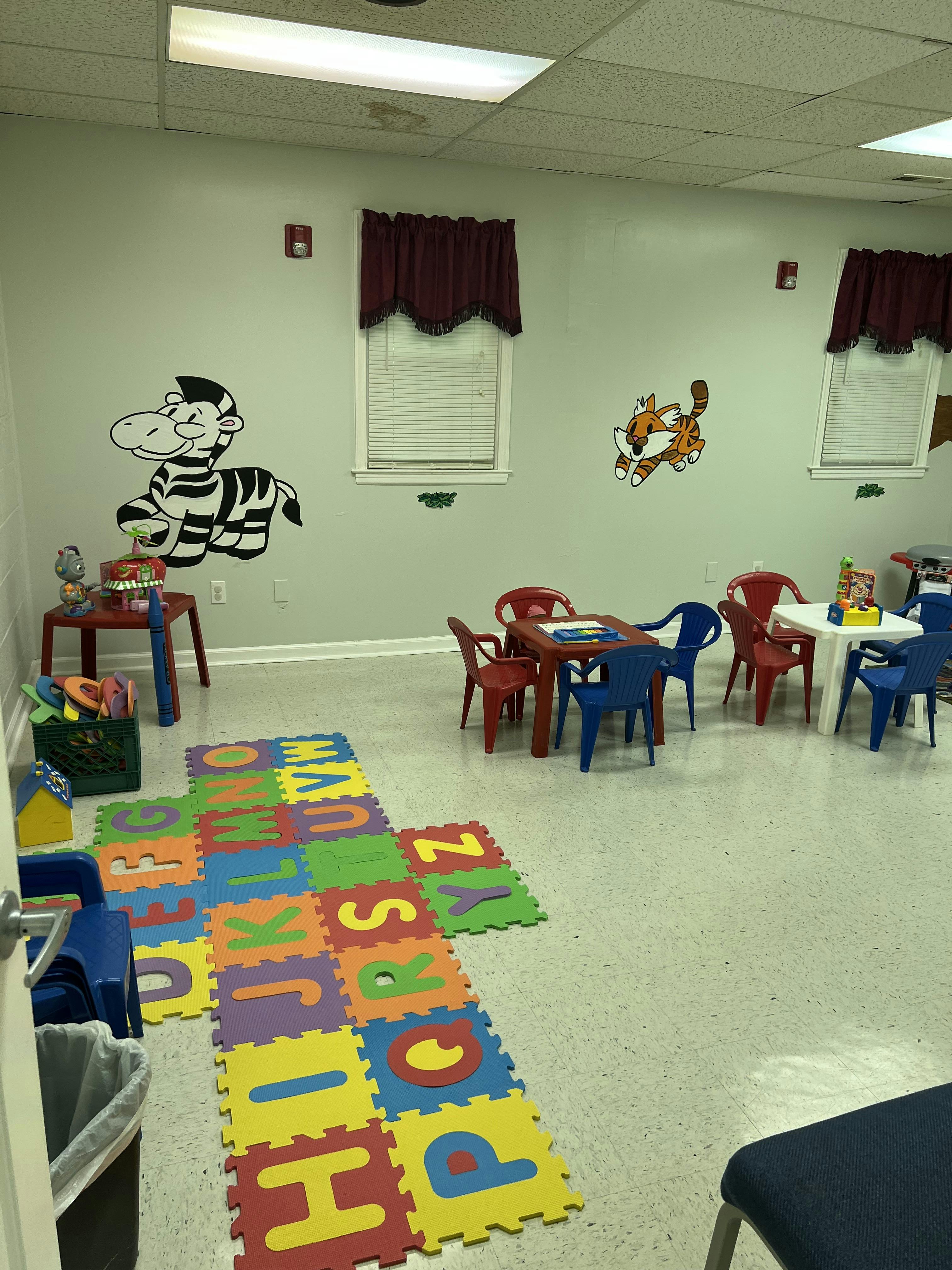 Playroom with alphabet floor mats, small tables, and chairs