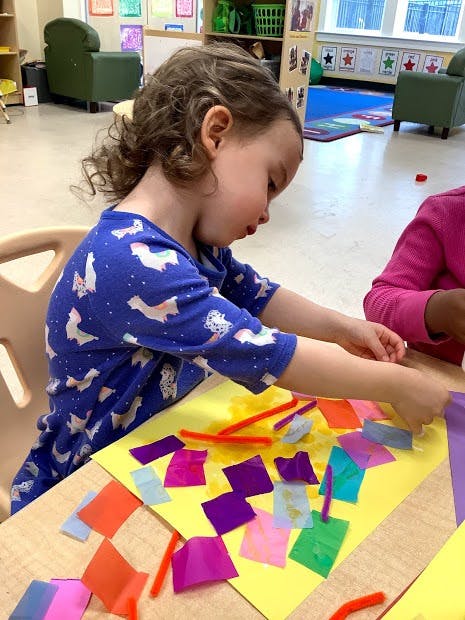 Child doing an art project with colorful paper and pipe cleaners