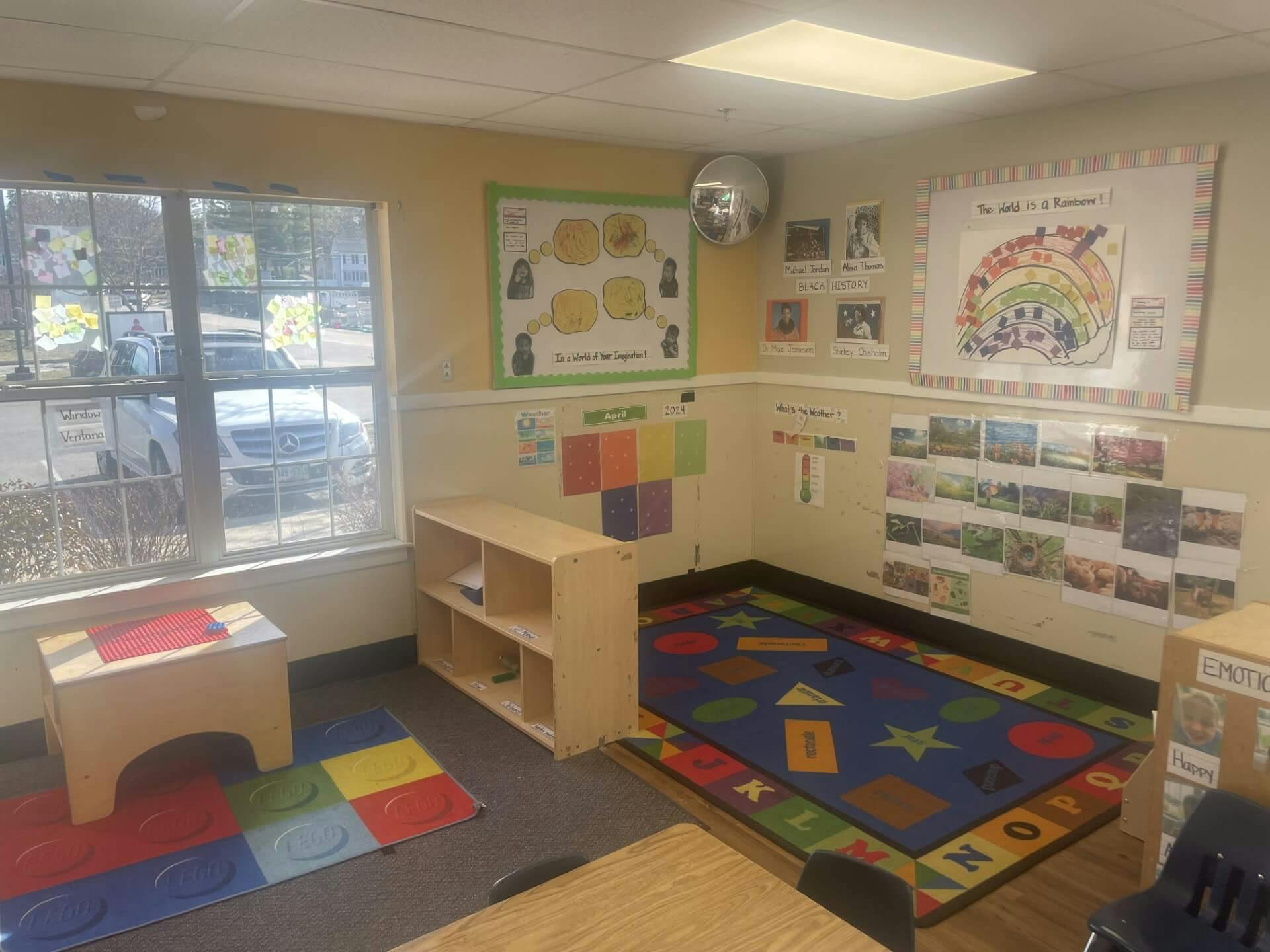 Classroom with child-sized furniture and colorful rugs with educational posters on the walls