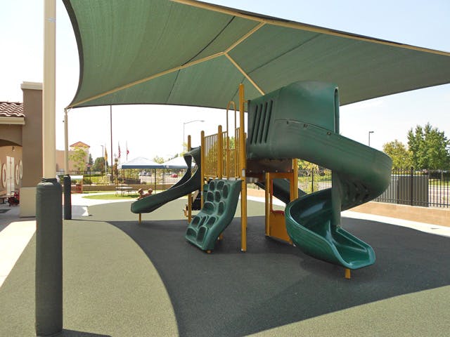 Playground with green slides and a green shade canopy