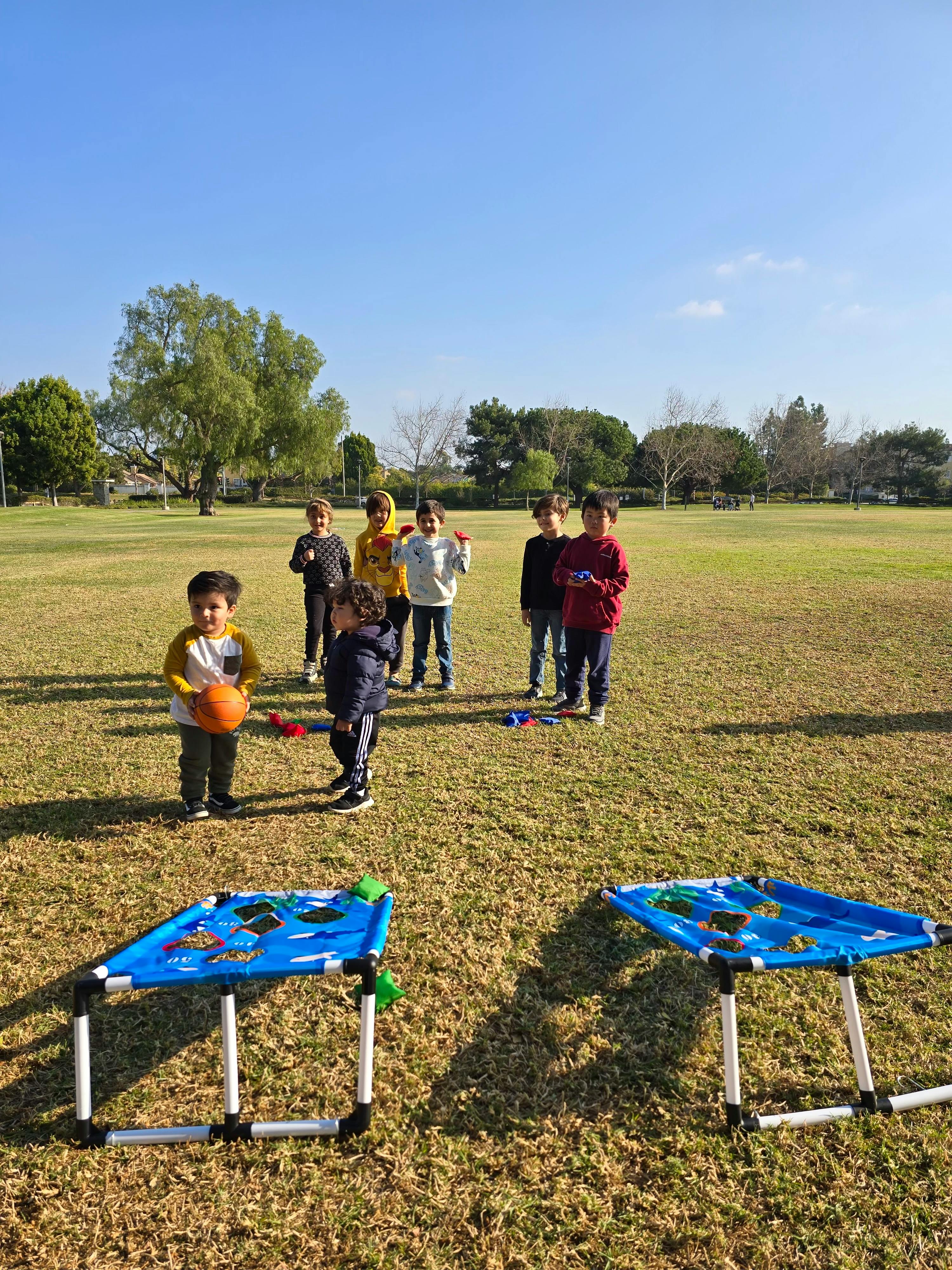 Children playing with a ball and beanbag toss games in a grassy field