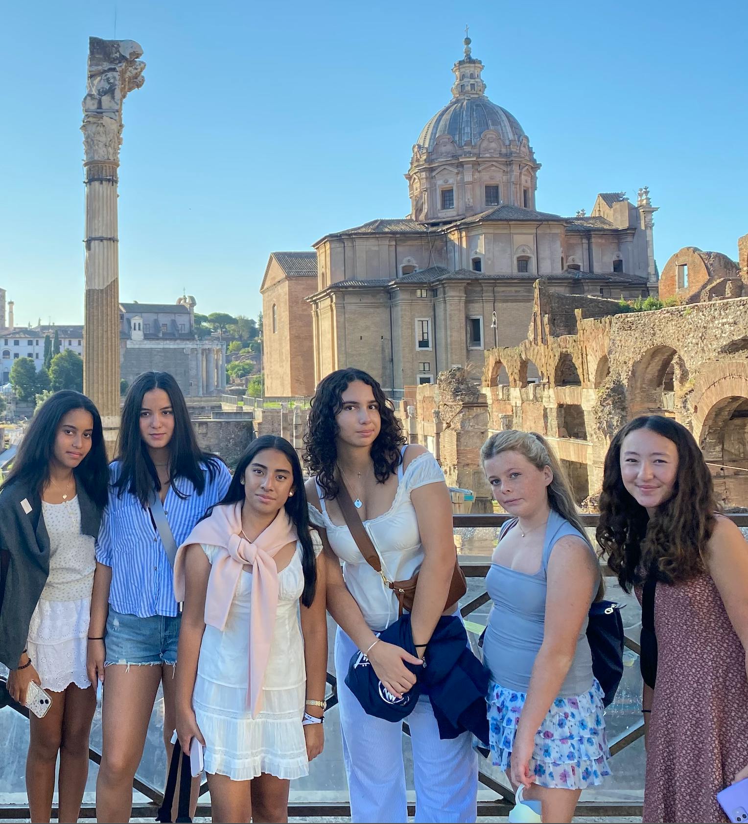 Six teens posing for a photo in front of ancient ruins and a dome building