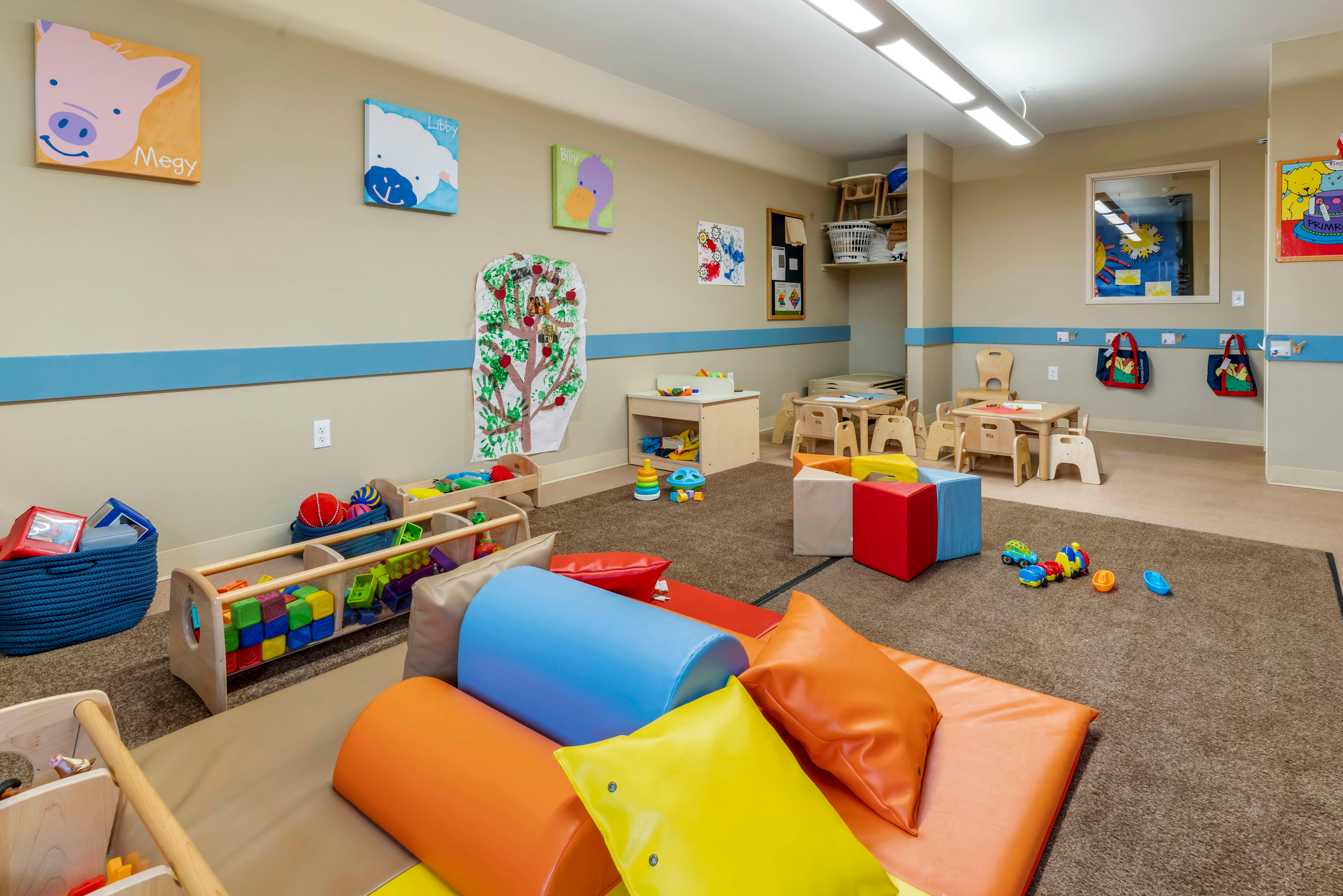 A colorful childcare classroom with various play equipment and small tables