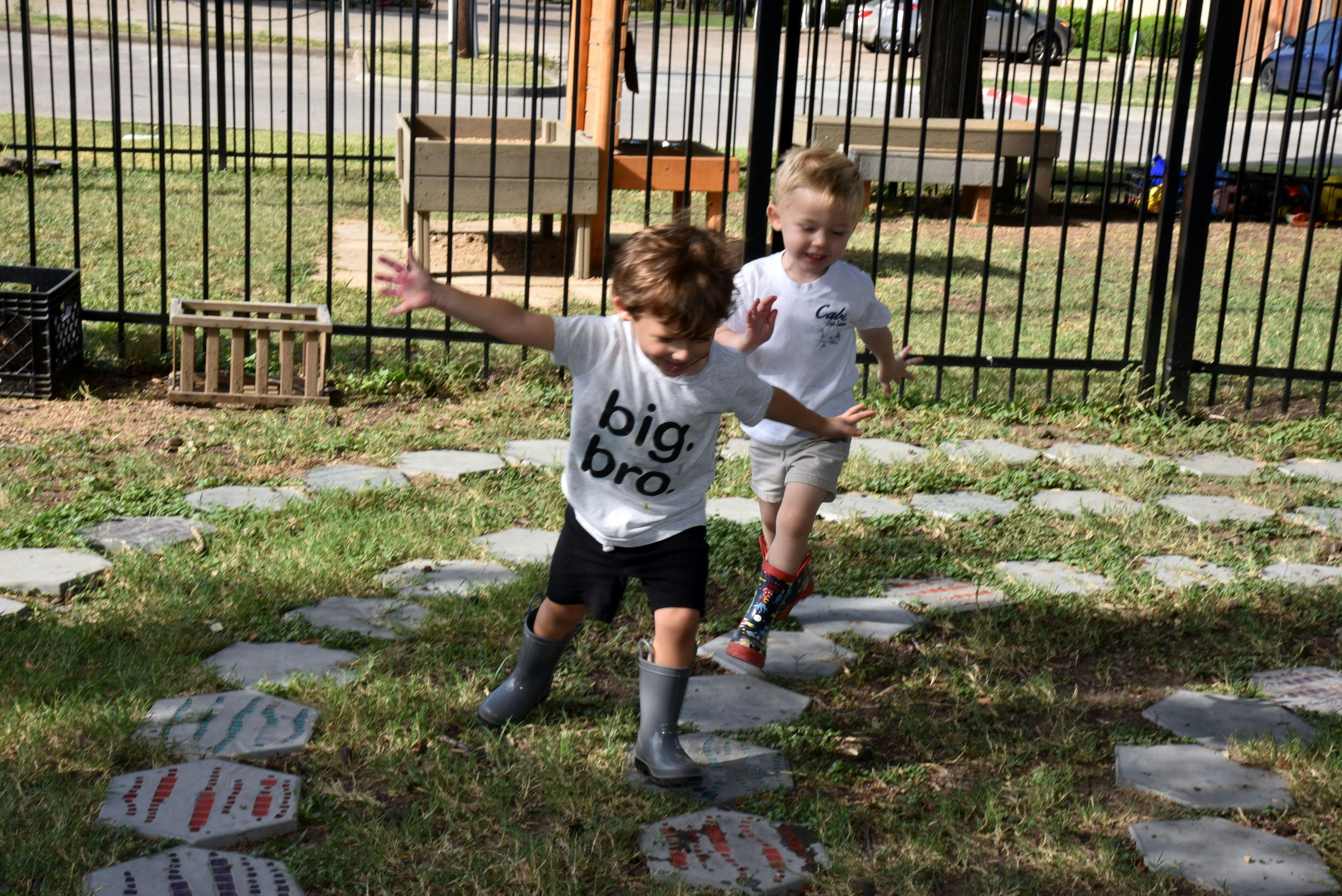 Two children walking on stepping stones in a grassy area