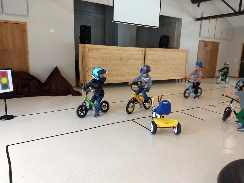 Children on bicycles and tricycles indoors