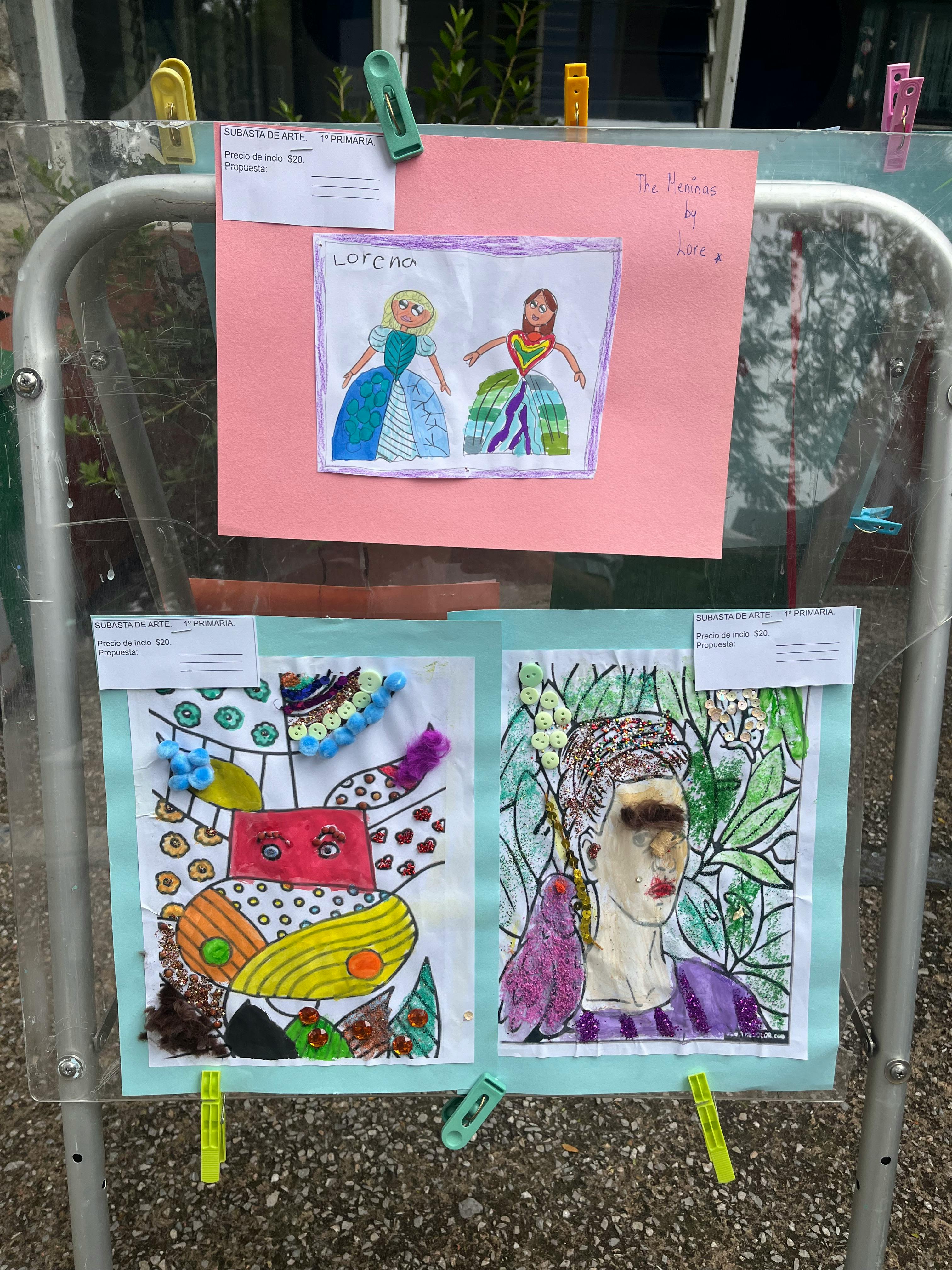 Children's artwork displayed outdoors with clothespins