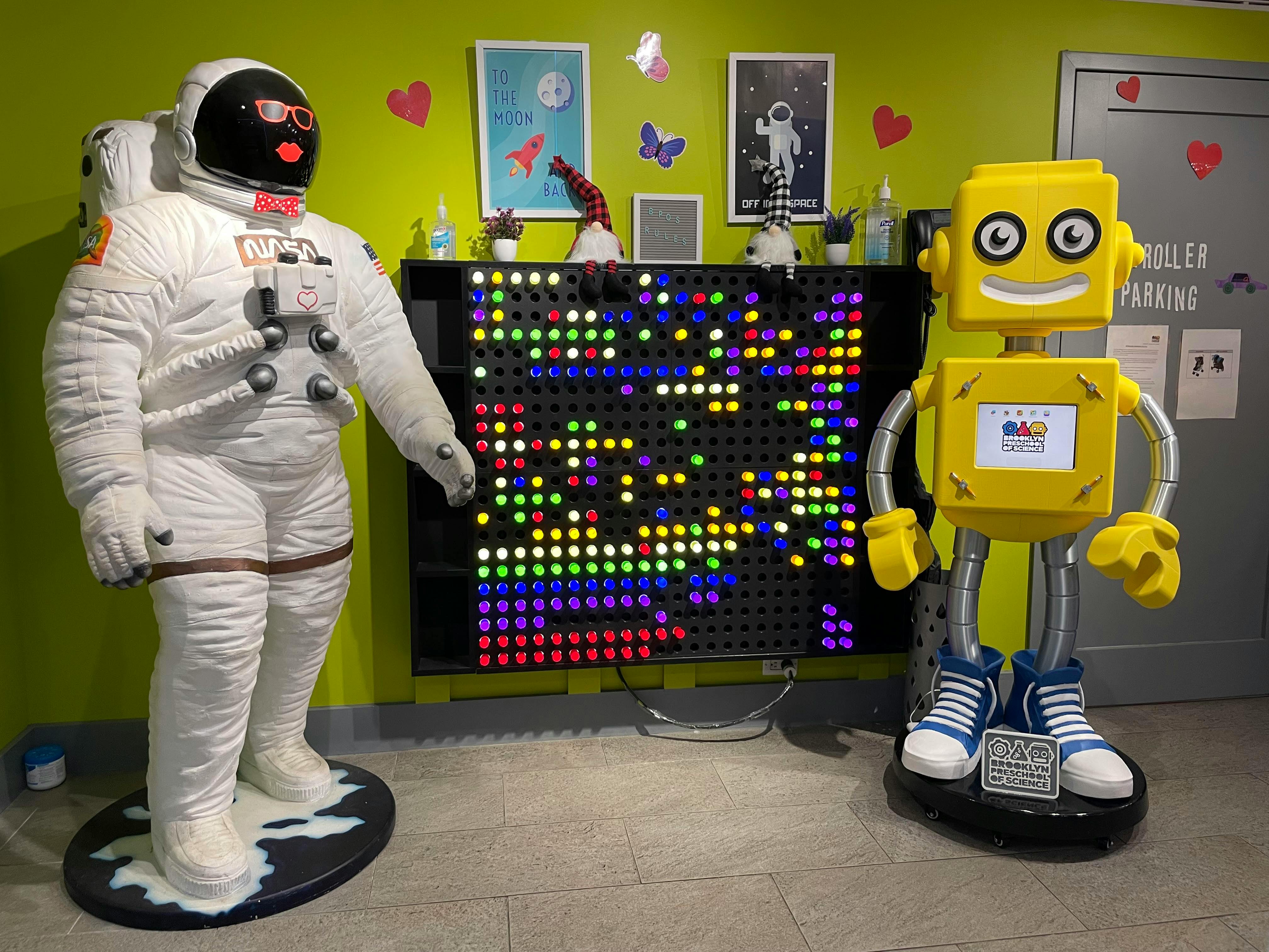 Astronaut and robot statues next to an interactive light board