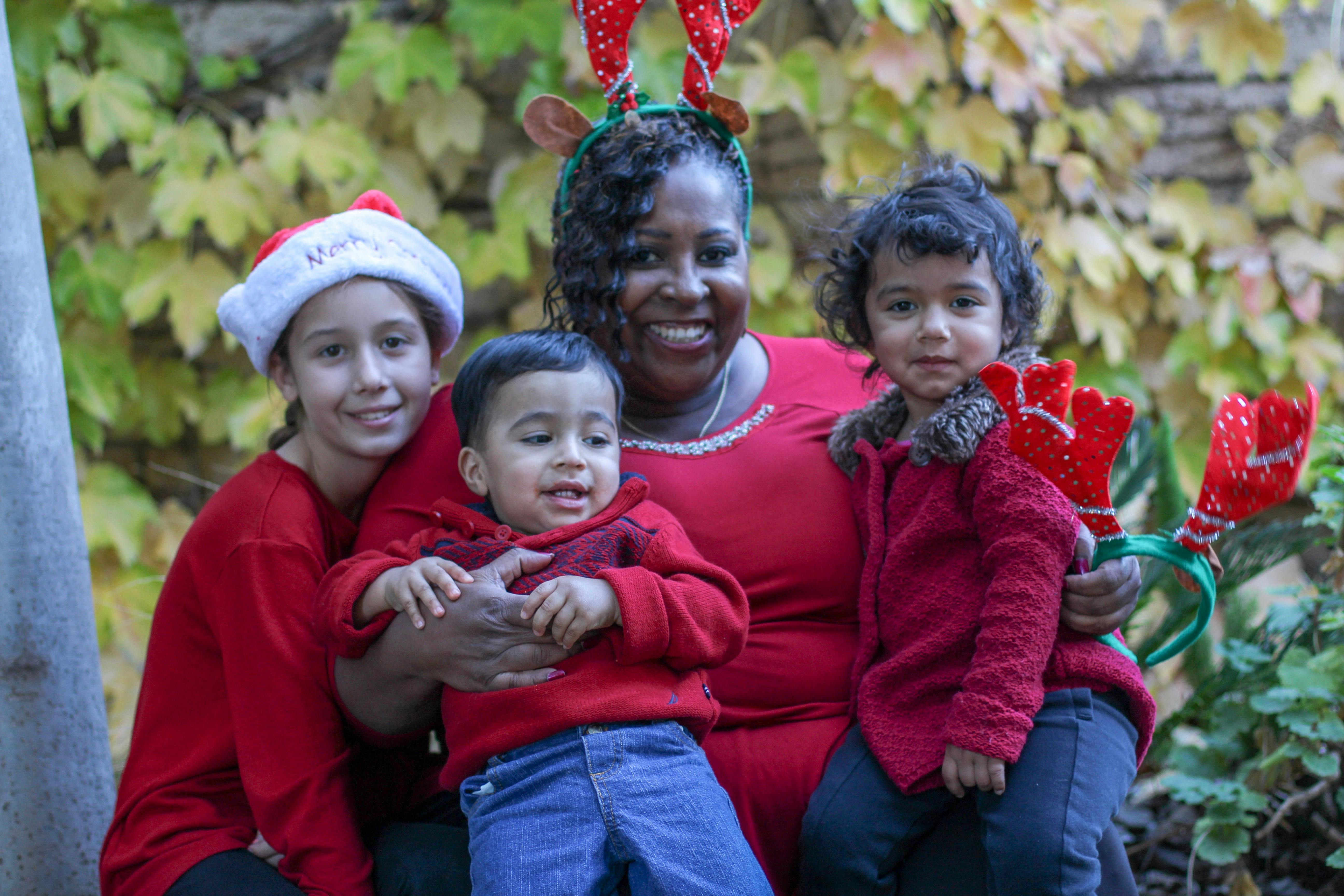 Person with two children and a teen, all wearing red and holiday accessories