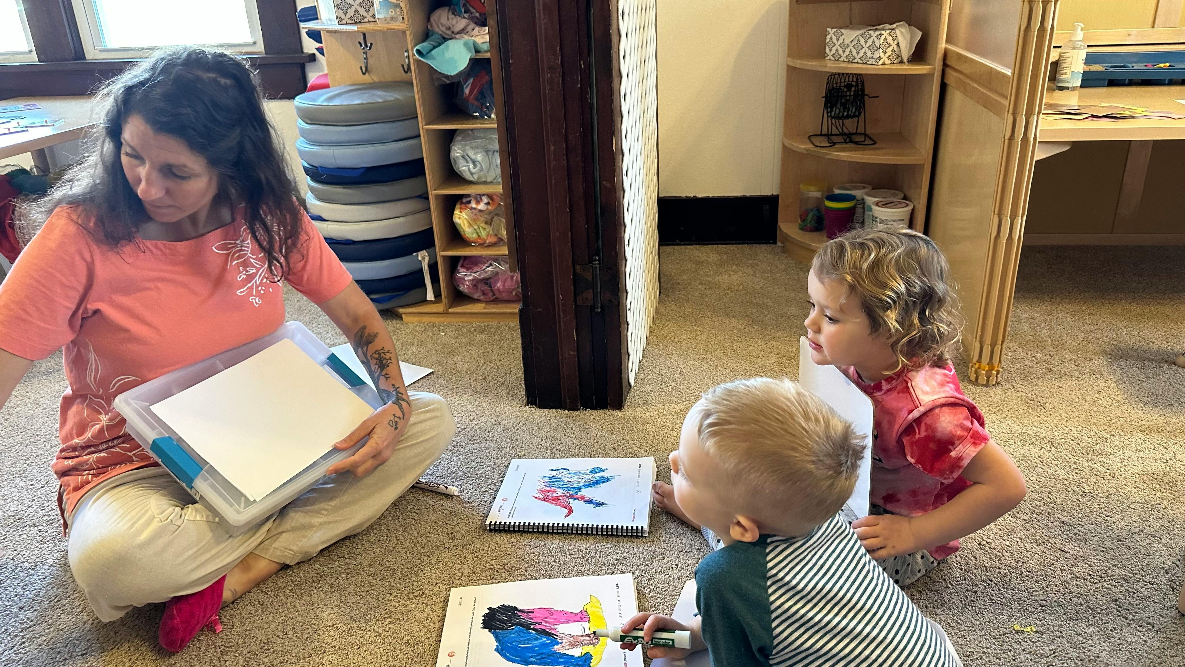 Person sitting on floor with two children looking at books