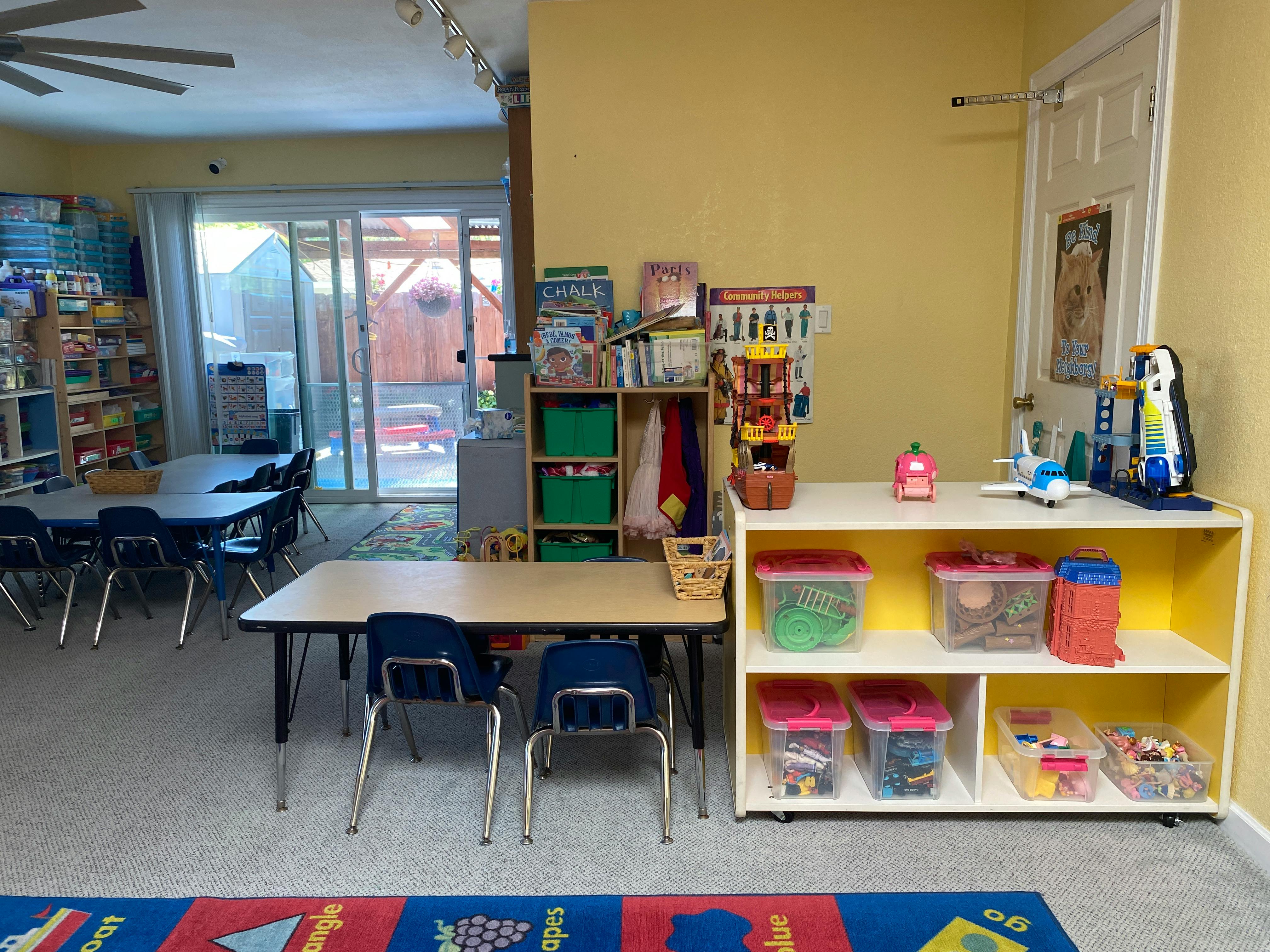 Classroom with tables, chairs, and shelves with toys and books