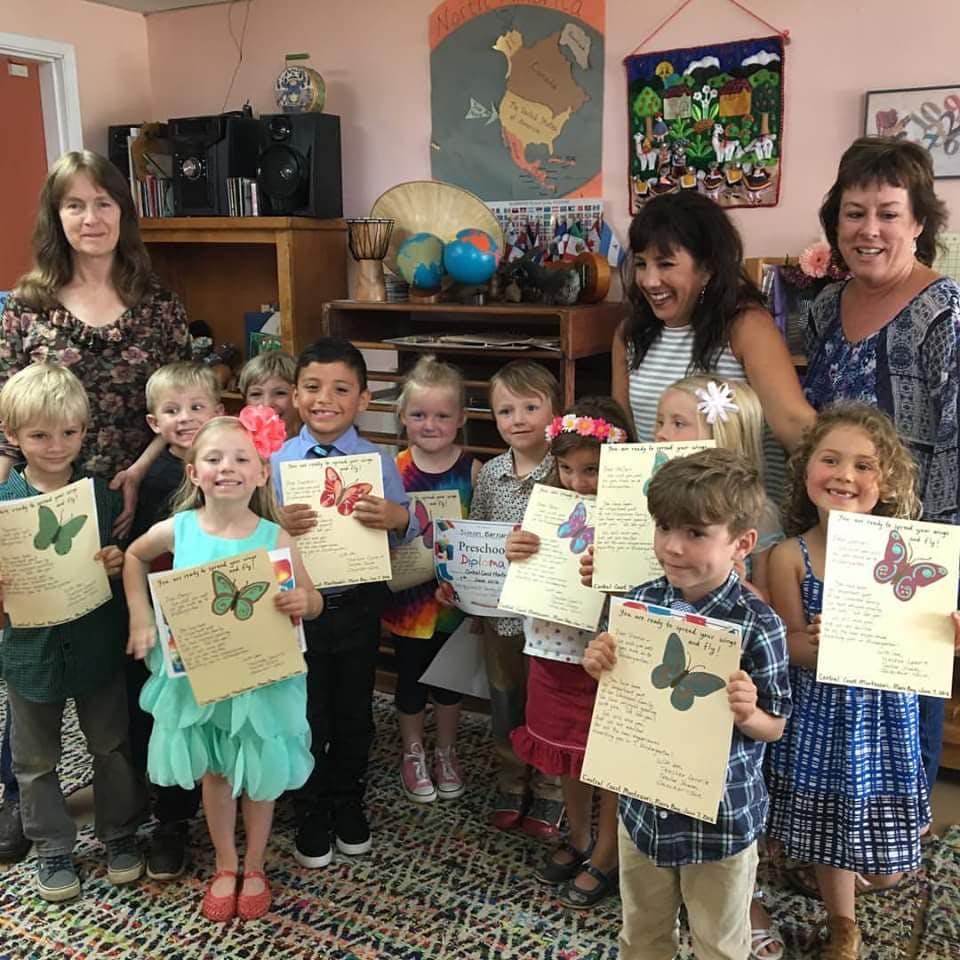 Adults and children holding up papers with butterfly drawings