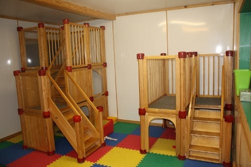 Indoor wooden play structures with stairs on a colorful mat