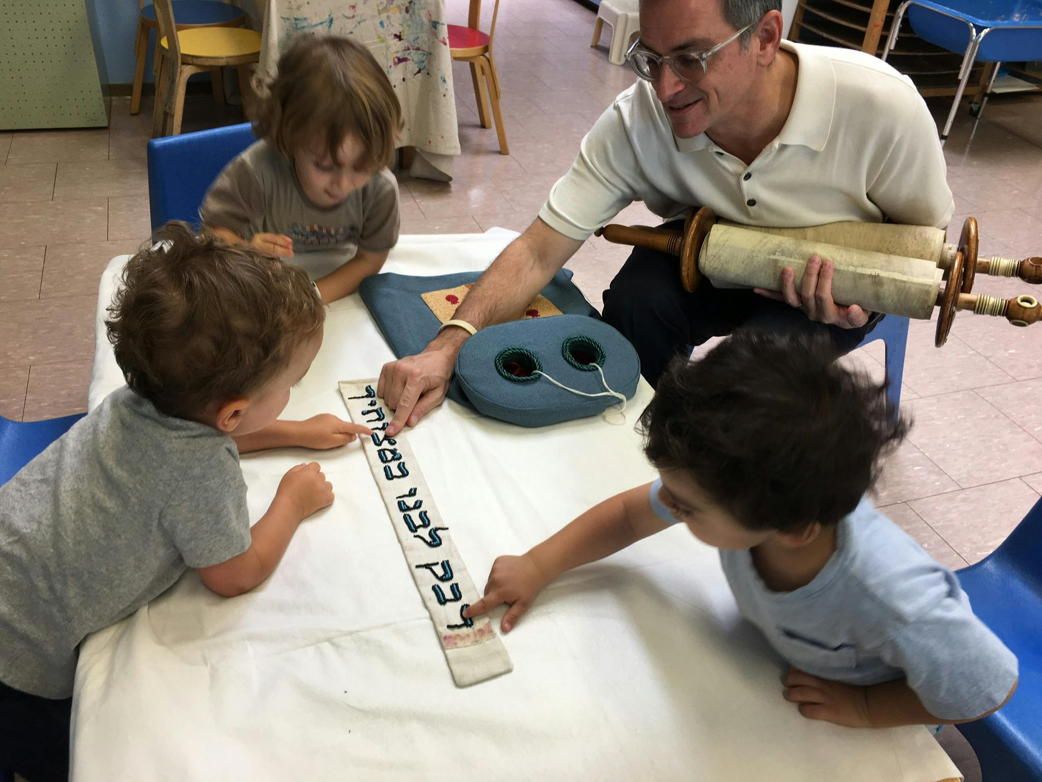 Adult and three children looking at a scroll with text