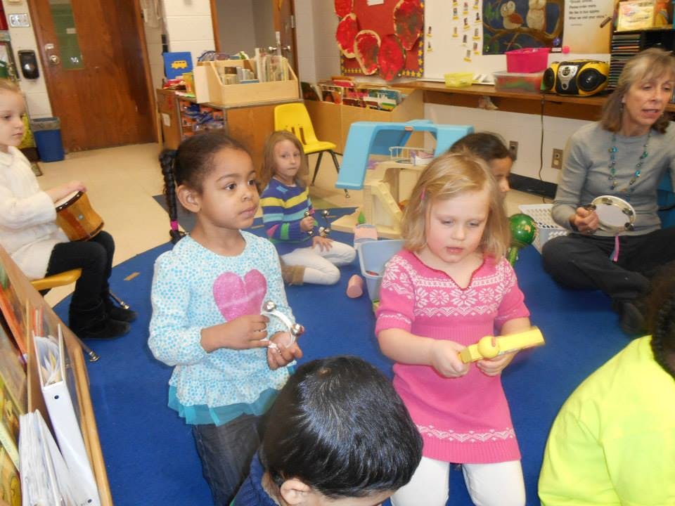 Children and an adult playing musical instruments in a classroom