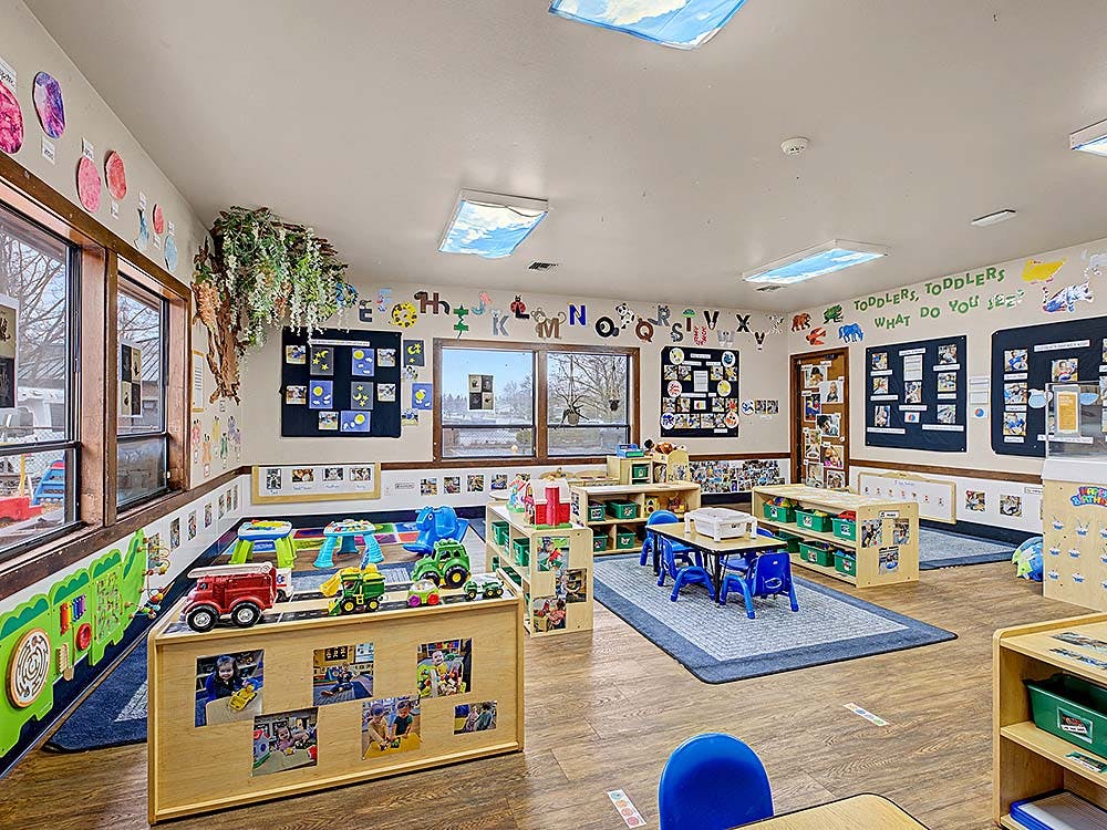 Classroom with tables, chairs, toys, and educational decorations on the walls