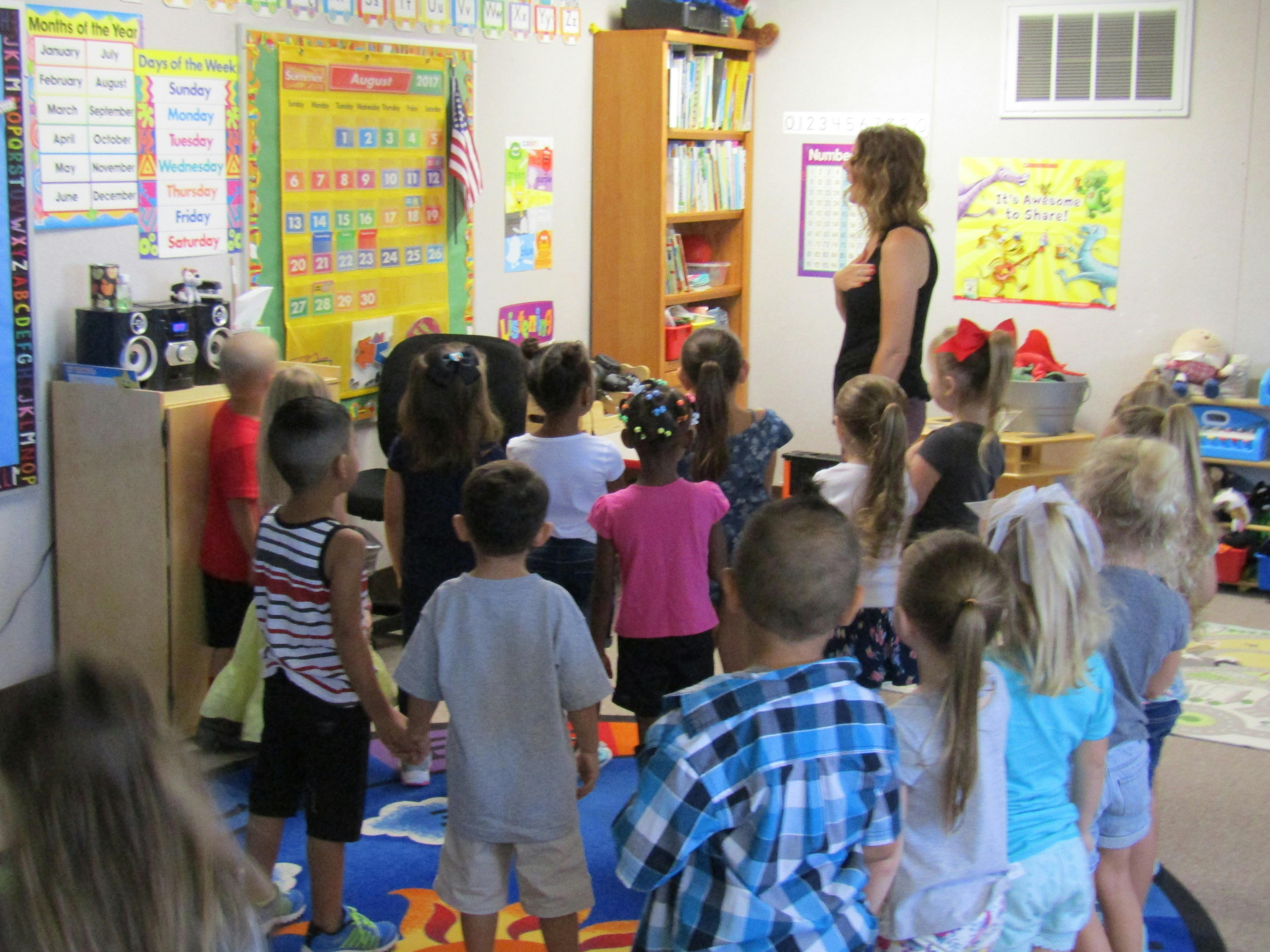 Adult person standing in front of a group of children in a classroom