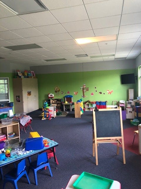 Classroom with green walls, blue carpet, and various toys and furniture