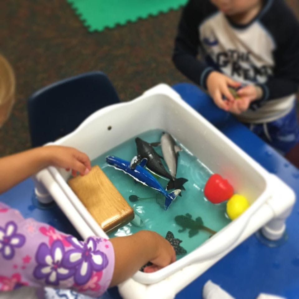 Child playing with toys in a water table