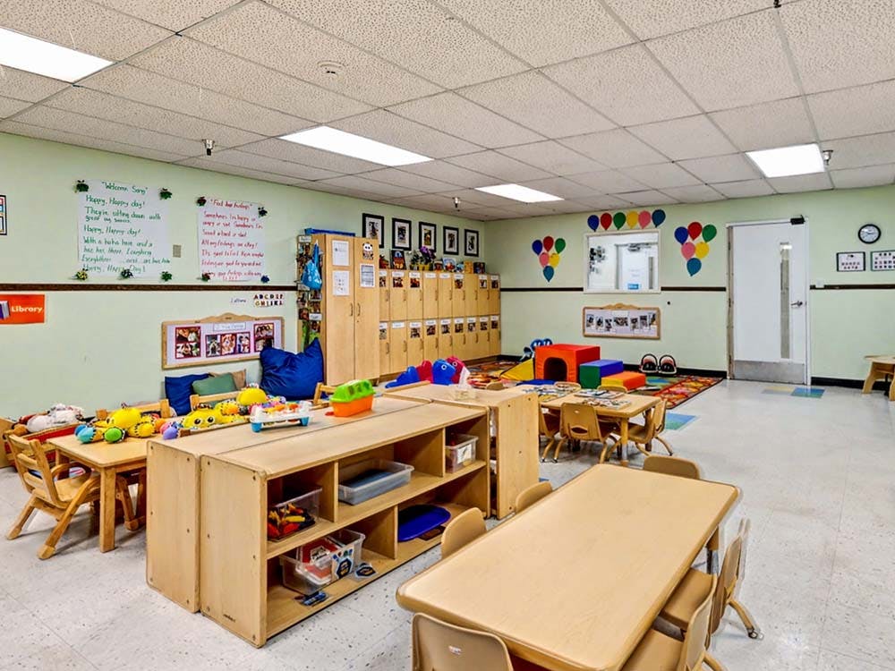 A colorful classroom with small tables, chairs, and cubbies