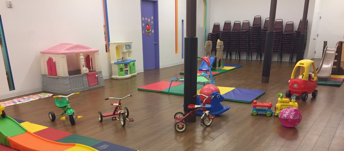 Indoor play area with tricycles, playhouse, and slide