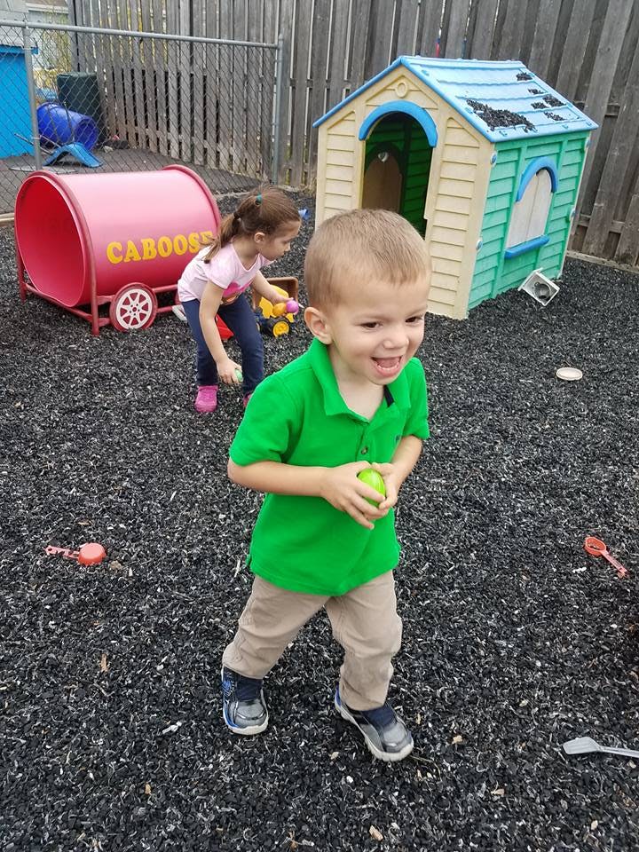 Child holding a ball on a playground with another child in the background
