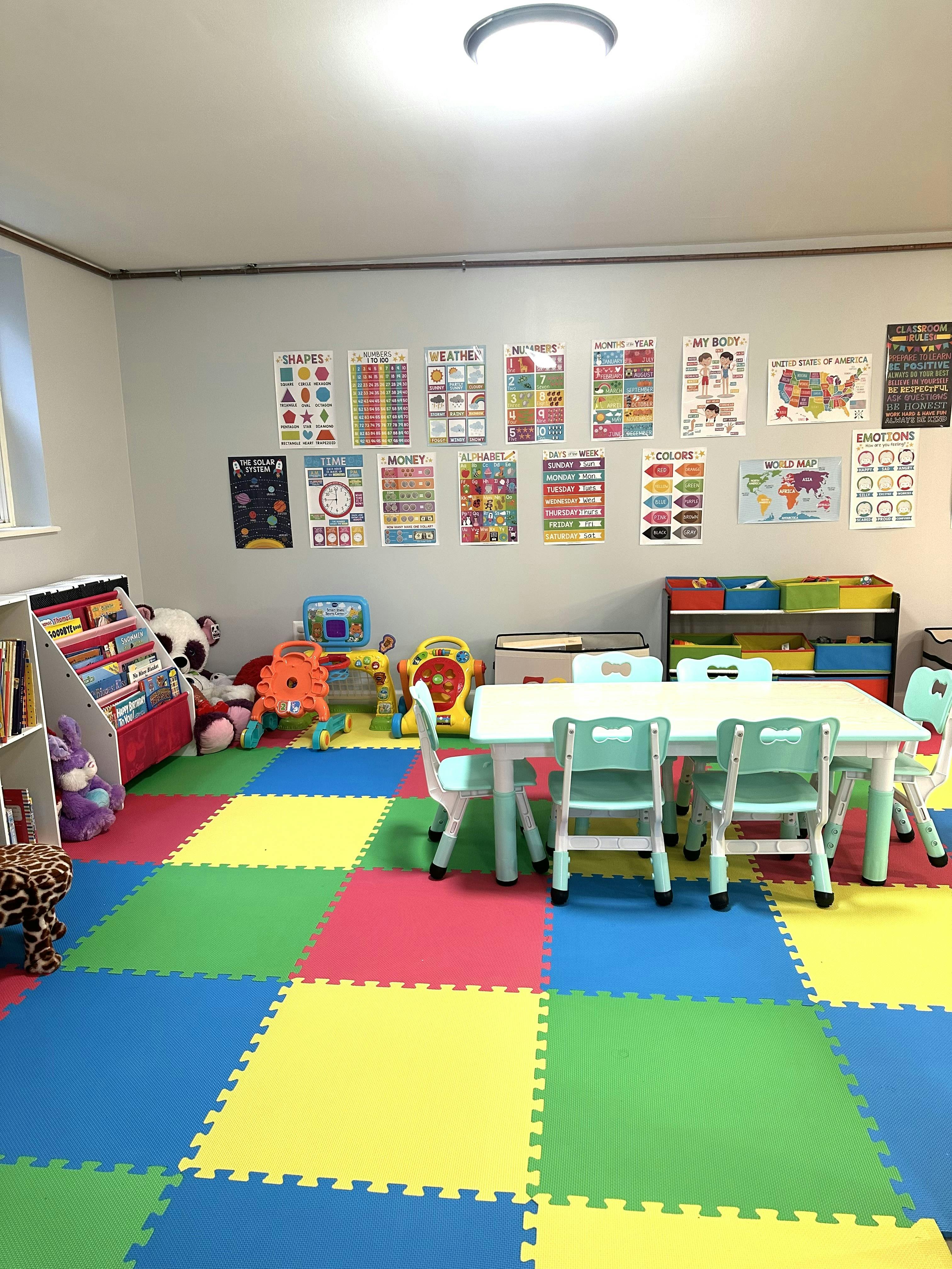 Classroom with colorful floor mats, a table and chairs, and educational posters on the wall