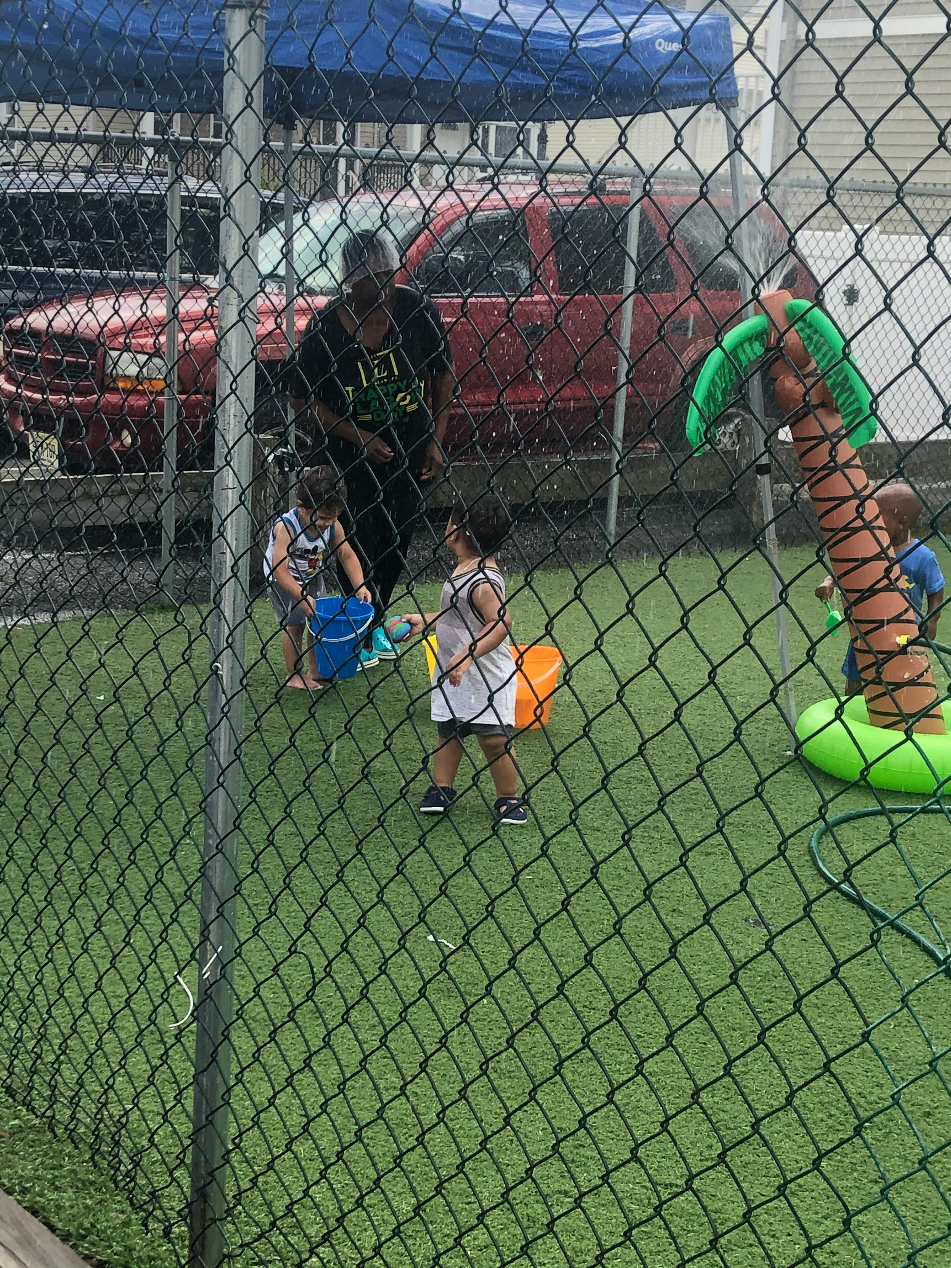 Person and children playing with buckets on artificial turf