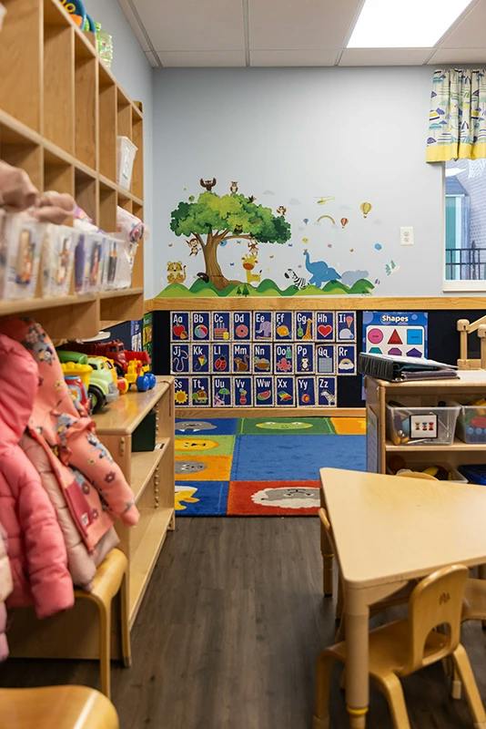 Classroom interior with small tables and an alphabet wall mural