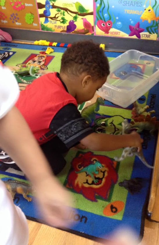 Child playing with toy dinosaurs on a colorful rug