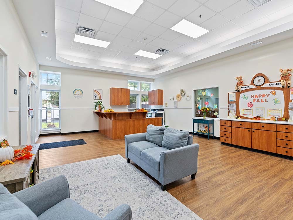 An empty waiting room with couches, a reception desk, and a "Happy Fall" sign