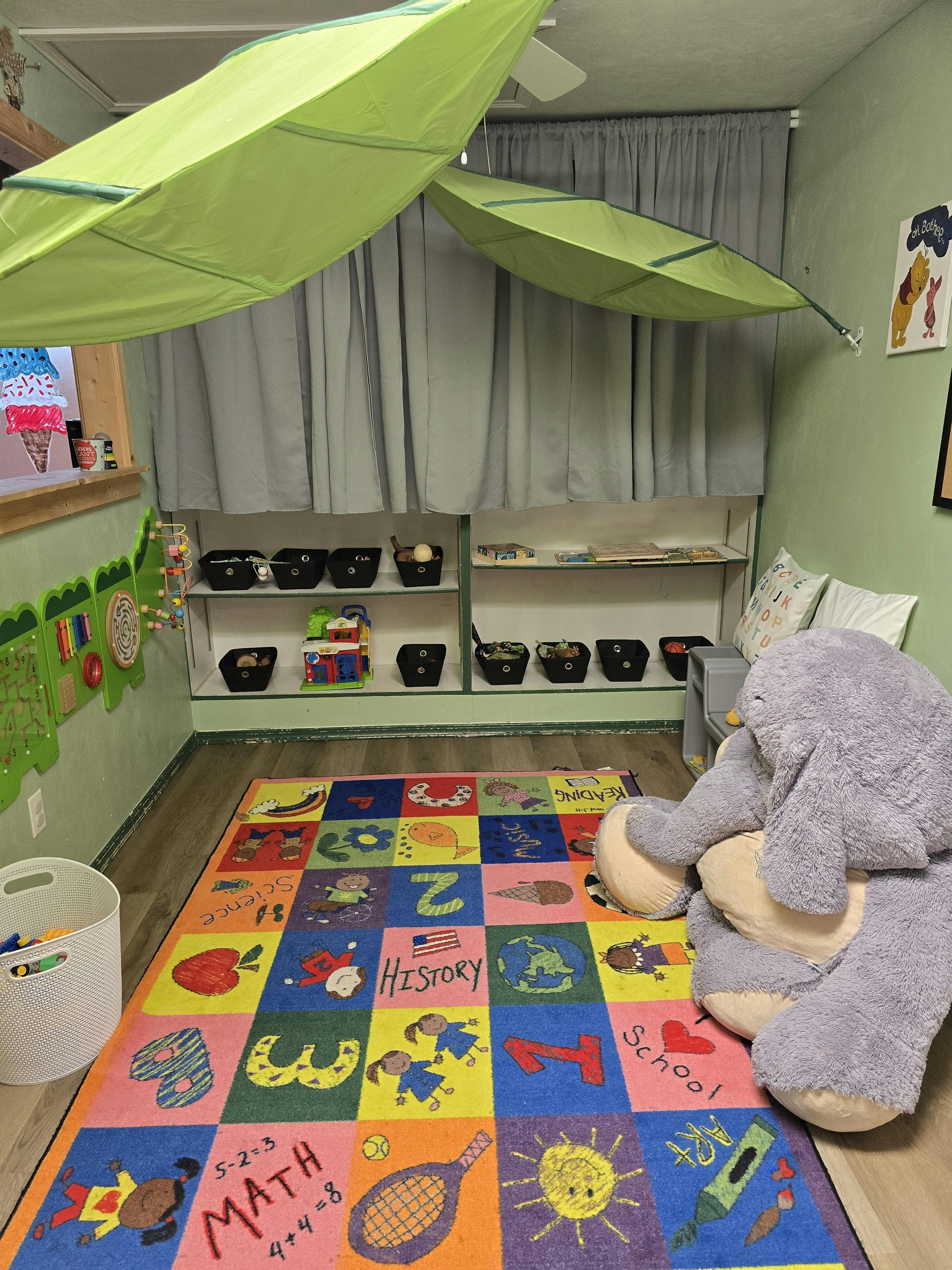 Colorful educational classroom with a learning rug and a large stuffed elephant