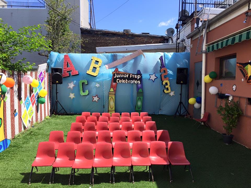 Rows of red chairs facing a backdrop with "Junior Prep Celebrates"