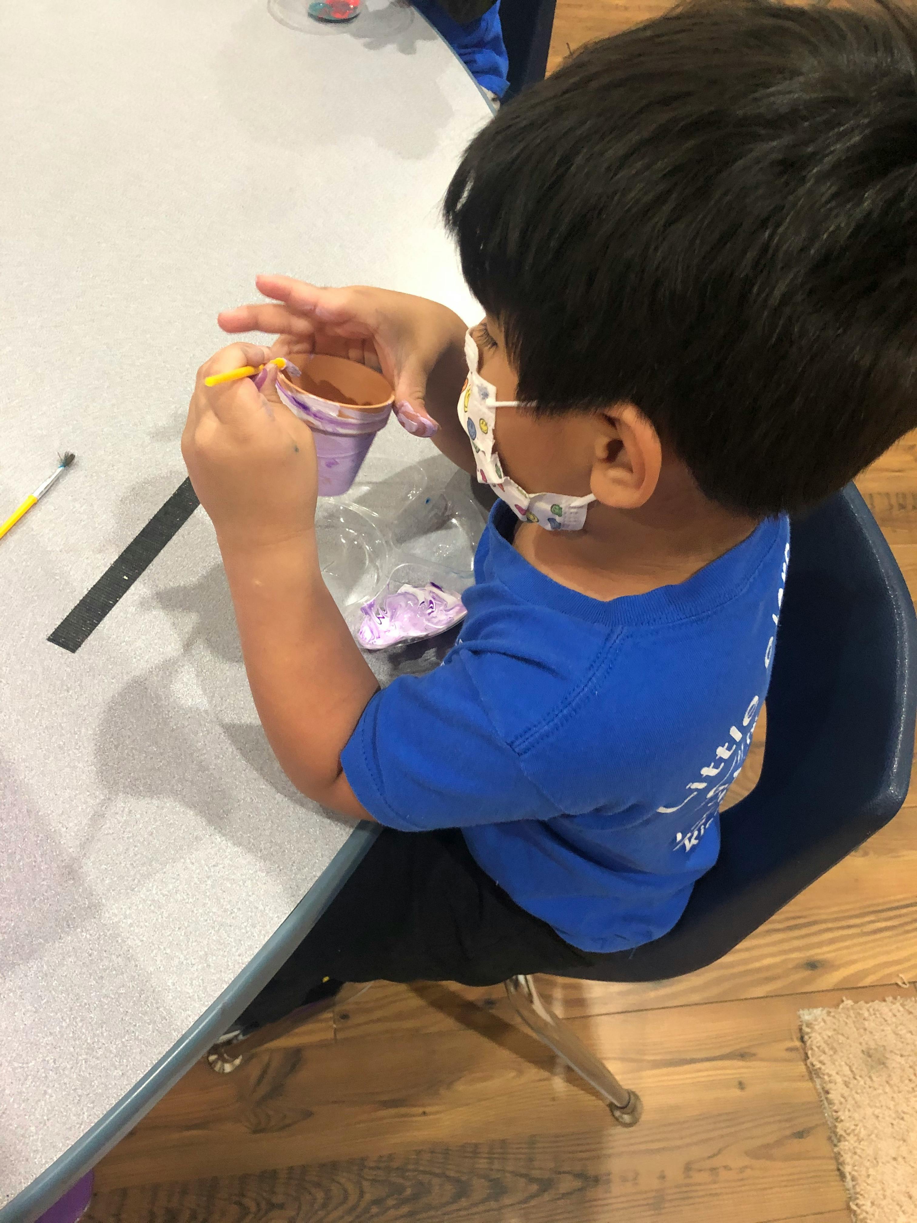 Child painting a small pot