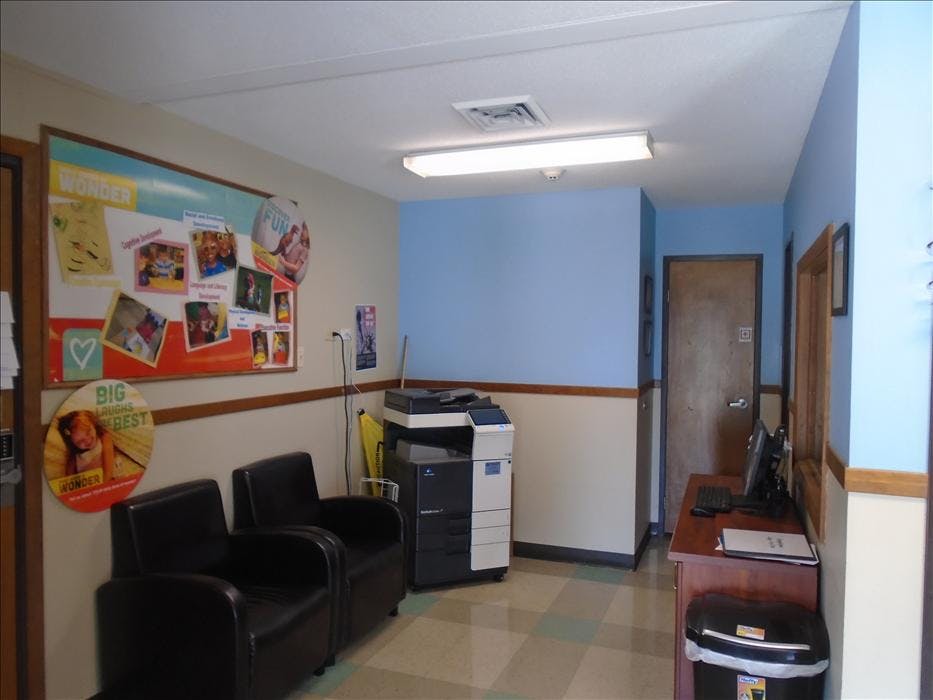 Waiting area with bulletin board, two chairs, a printer, and a desk