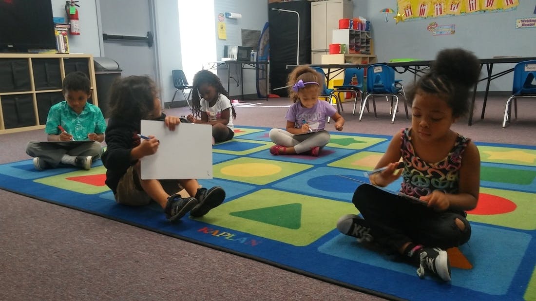 Children sitting on a colorful rug in a classroom