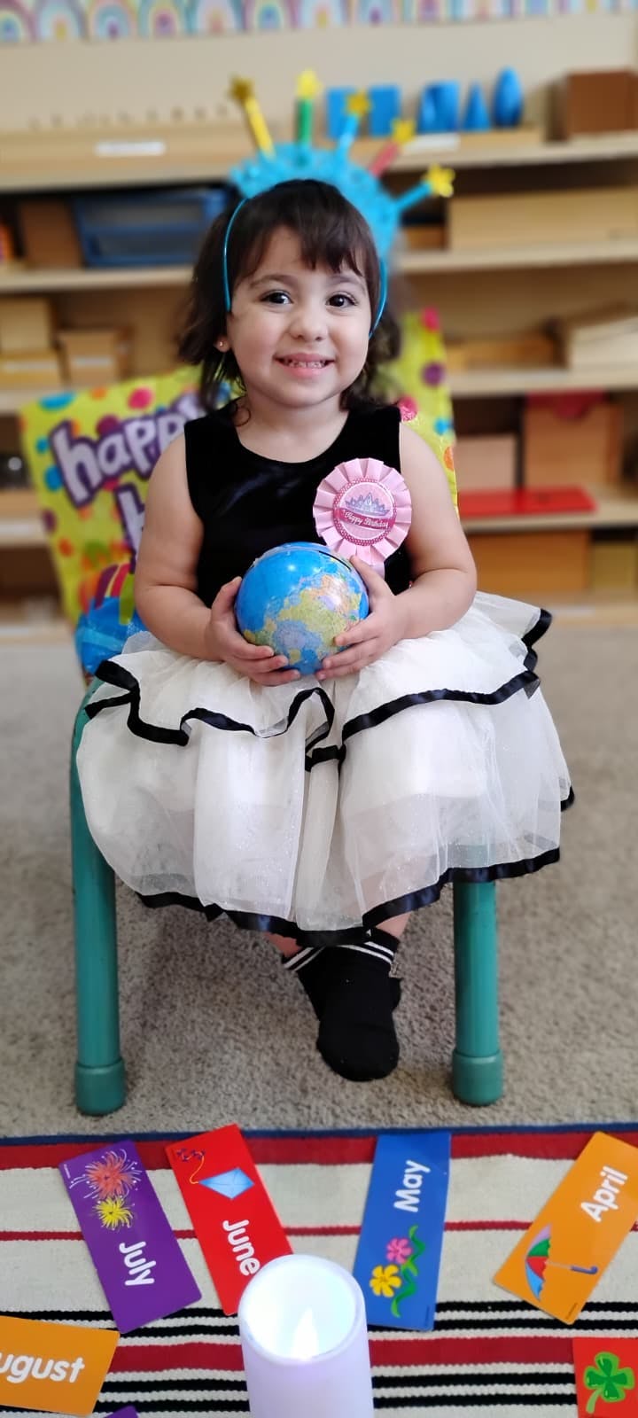 Child wearing a birthday crown and holding a small globe