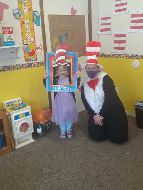 Child holding a Dr. Seuss frame and a person in a Cat in the Hat costume