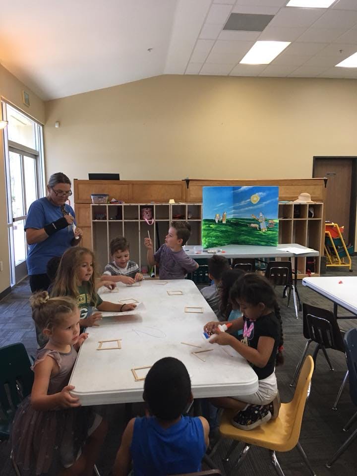 Adult and children sitting at a table in a classroom