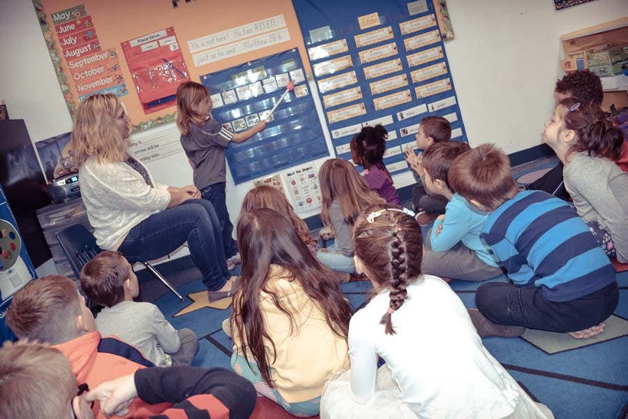 Adult and children in a classroom looking at a board