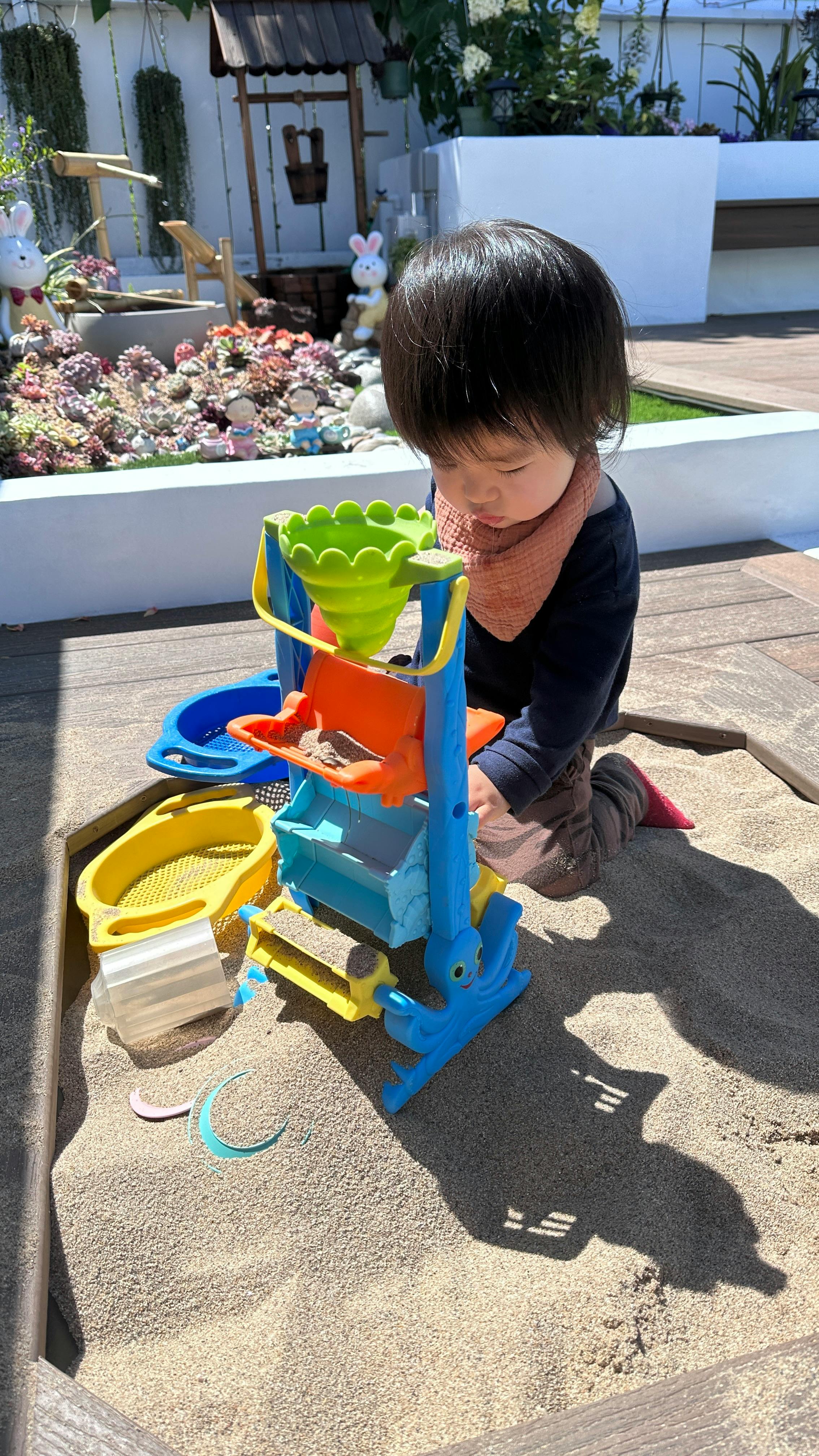 Child playing with a sand and water table in a sandbox