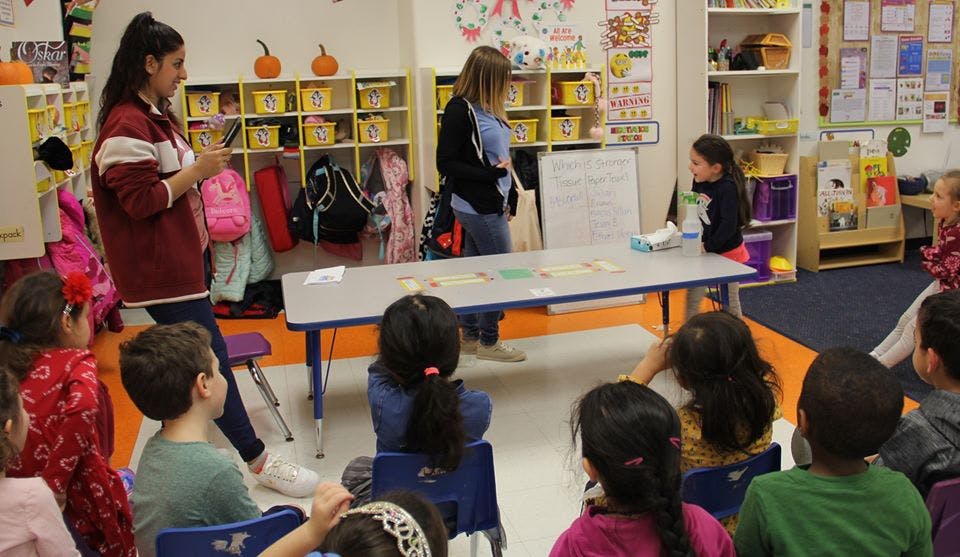 Two adults and multiple children in a classroom